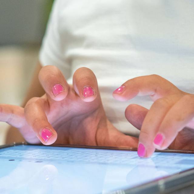 Eine Person tippt auf einem Tablet etwas ein.