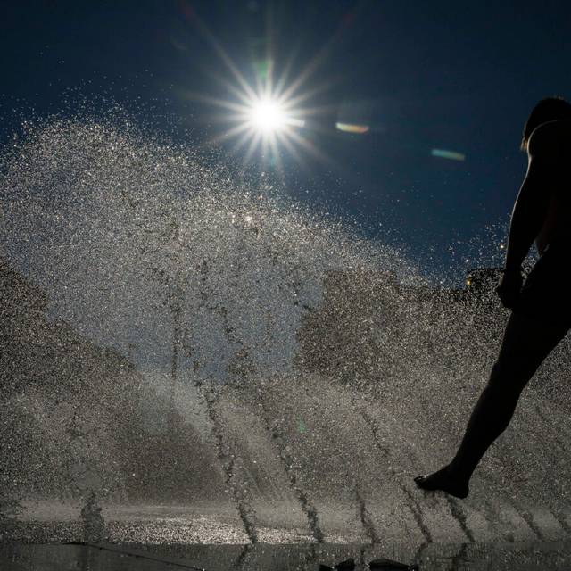 Ein Mann kühlt sich an einem Brunnen am Stachus in der Innenstadt im Wasser ab.