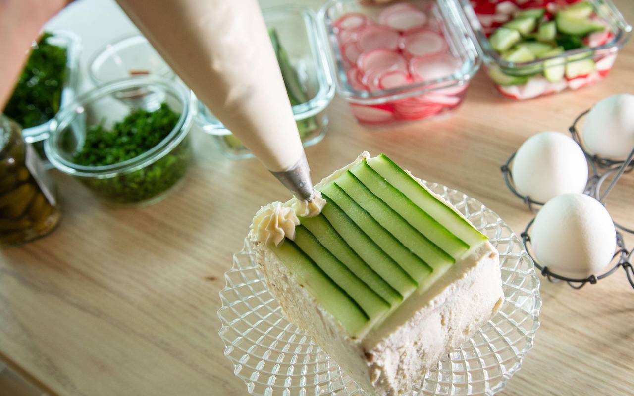 Brottorte wird mit Frischkäse und Gurke dekoriert