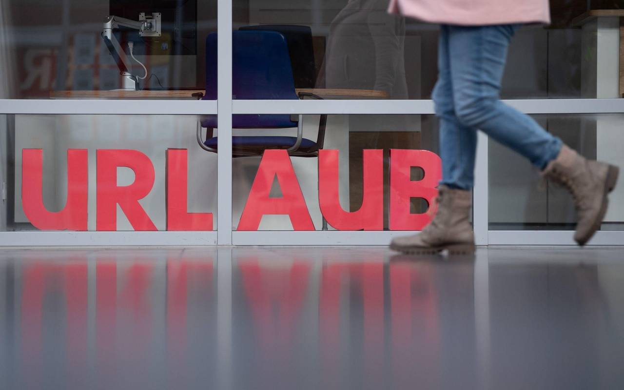 Eine Frau läuft an den Buchstaben Urlaub vorbei