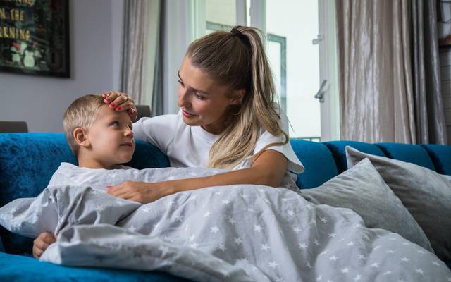 Eine Mutter legt ihre Hand auf die Stirn ihres Sohnes