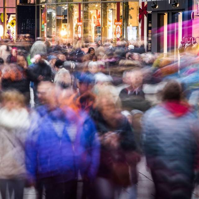 Passanten gehen vor Heiligabend über eine Einkaufsmeile