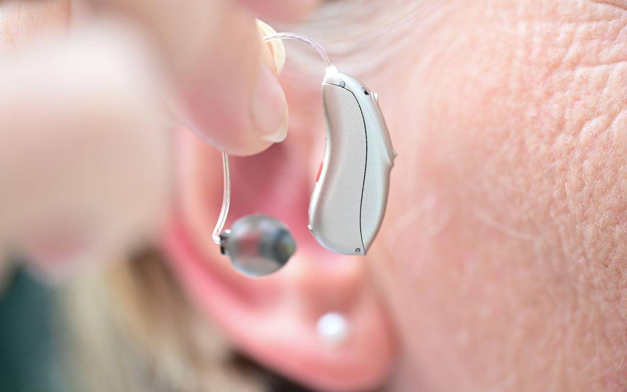 Eine Frau hält ein Hörgerät vor ihr Ohr