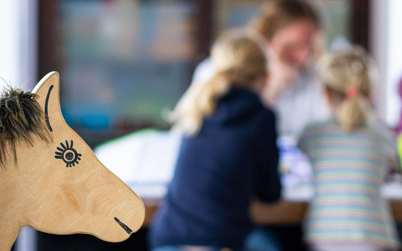 Ein Elternteil sitzt mit seinen Kindern an einem Tisch