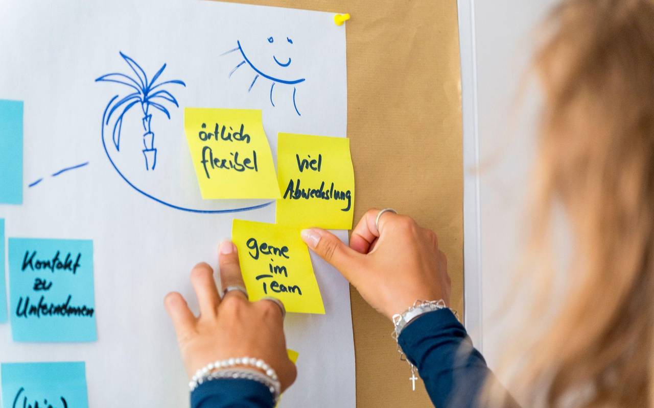 Eine Frau klebt Post-Its an eine Wand