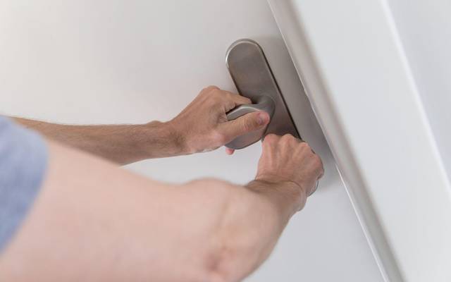 Mann schließt eine Wohnungstür ab