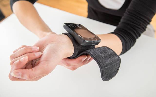Frau misst ihren Blutdruck am Handgelenk