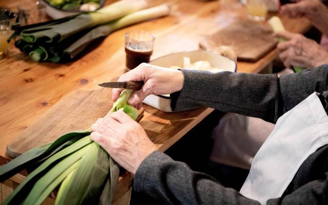 Eine Seniorin schneidet Lauch klein
