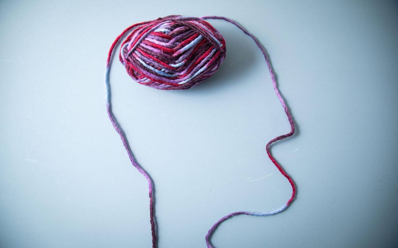 Die Silhouette eines Menschen und dessen Gehirn aus Garn