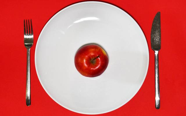 Ein Apfel liegt zum Verzehr bereit auf einem Teller