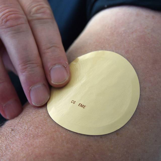 Eine Person trägt ein Wirkstoffpflaster am Oberarm