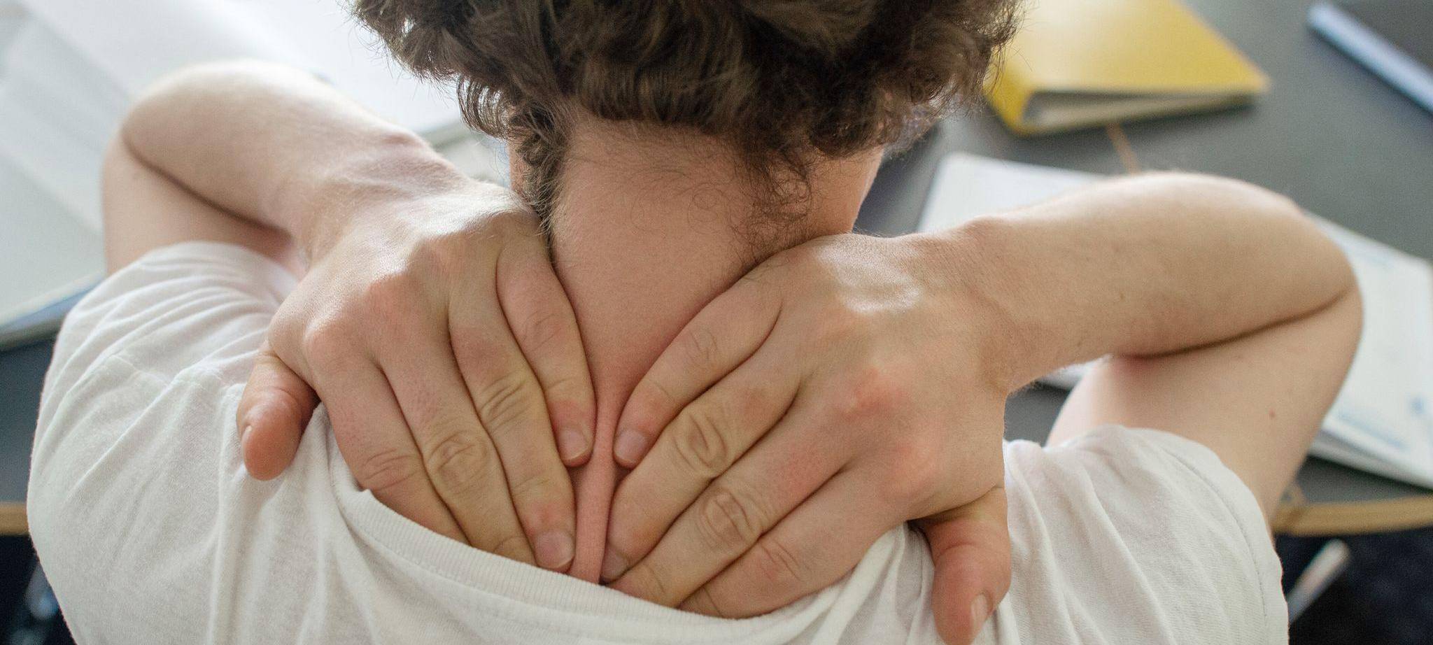 Ein Mann greif tmi beiden Händen seinen Nacken