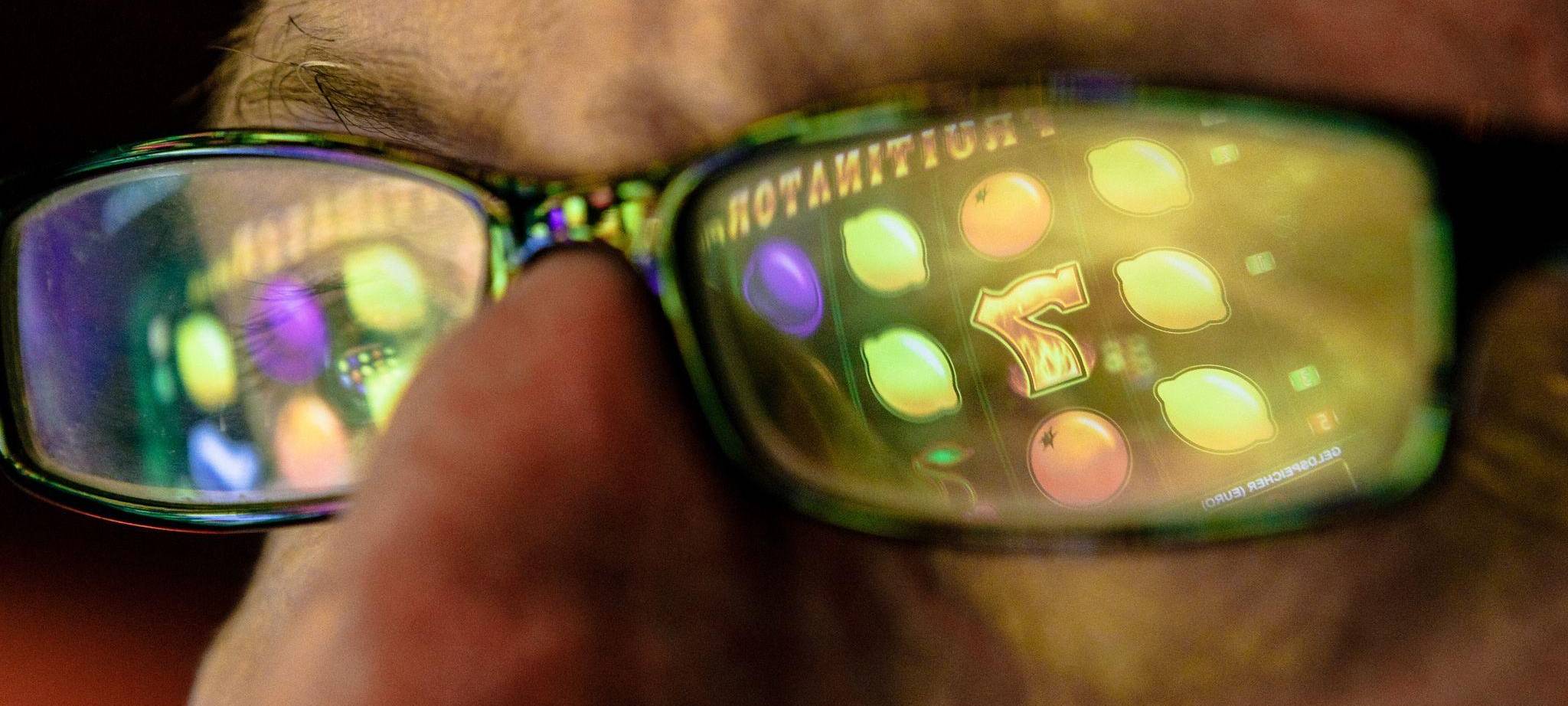 Symbole eines Spielautomaten spiegeln sich in einer Brille
